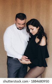 Pregnancy Photo Session In A Photo Studio With A Fabric Background In A Black Bodysuit And Tights