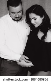 Pregnancy Photo Session In A Photo Studio With A Fabric Background In A Black Bodysuit And Tights