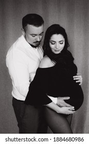 Pregnancy Photo Session In A Photo Studio With A Fabric Background In A Black Bodysuit And Tights