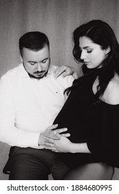 Pregnancy Photo Session In A Photo Studio With A Fabric Background In A Black Bodysuit And Tights