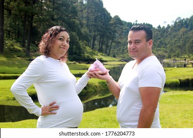 
Pregnancy Photoshoot Of Latin Couple With Pink Baby Shoes In Forest