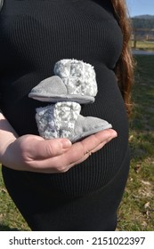 A Pregnancy Photoshoot With Mini Shoes In Front 