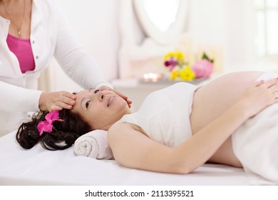 Pregnancy Spa Treatment. Massage For Pregnant Woman. Asian Expectant Mom Enjoying Wellness Day. Relax And Meditation. New Mom Relaxing In Health Care Clinic. Pampering Time For Expecting Mother.