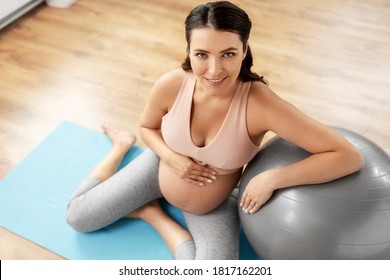 Pregnancy, Sport And Fitness Concept - Happy Smiling Pregnant Woman Exercising With Fitball At Home