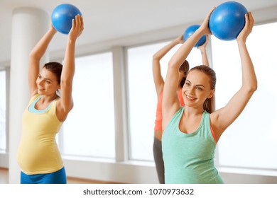 pregnancy, sport, fitness and healthy lifestyle concept - group of happy pregnant women training with small exercise balls in gym
