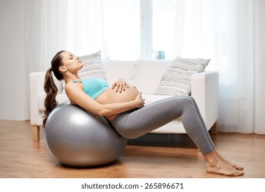 Pregnancy, Sport, Fitness, People And Healthy Lifestyle Concept - Happy Pregnant Woman Exercising On Fitball At Home