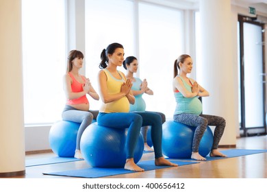 Pregnancy, Sport, Fitness, People And Healthy Lifestyle Concept - Group Of Happy Pregnant Women Exercising On Ball In Gym