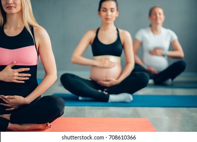 pregnancy, sport, fitness, people and healthy lifestyle concept - group of happy pregnant women exercising yoga and and meditating in lotus pose in gym