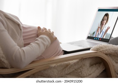 Pregnancy and telehealth. Close up of young female touch baby bump sit by laptop pc get gp attending physician advices by video call. Pregnant woman communicate to doctor using online health service