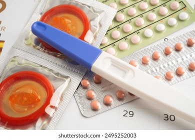 Pregnancy test and birth control pills on calendar, contraception health and medicine. - Powered by Shutterstock