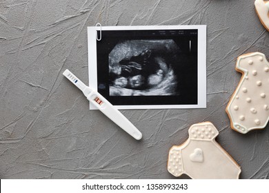 Pregnancy test, sonogram image and cookies on grey background
