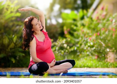 Pregnancy yoga. Exercise for pregnant woman. Active Asian female exercising at home or gym. New expectant mom keeping active and fit before childbirth. Sport for expecting mother. Online class.