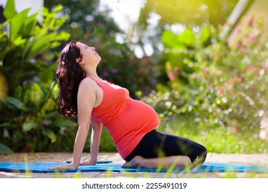 Pregnancy yoga. Exercise for pregnant woman. Active Asian female exercising at home or gym. New expectant mom keeping active and fit before childbirth. Sport for expecting mother. Online class. - Shutterstock ID 2255491019