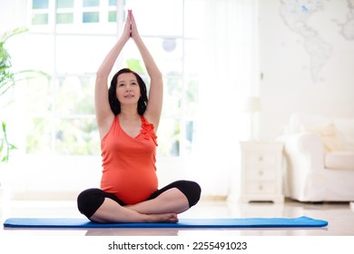 Pregnancy yoga. Exercise for pregnant woman. Active Asian female exercising at home or gym. New expectant mom keeping active and fit before childbirth. Sport for expecting mother. Online class. - Shutterstock ID 2255491023
