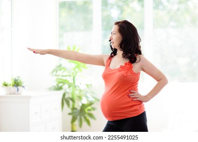Pregnancy yoga. Exercise for pregnant woman. Active Asian female exercising at home or gym. New expectant mom keeping active and fit before childbirth. Sport for expecting mother. Online class. - Shutterstock ID 2255491025