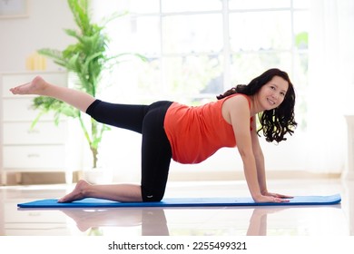 Pregnancy yoga. Exercise for pregnant woman. Active Asian female exercising at home or gym. New expectant mom keeping active and fit before childbirth. Sport for expecting mother. Online class. - Shutterstock ID 2255499321