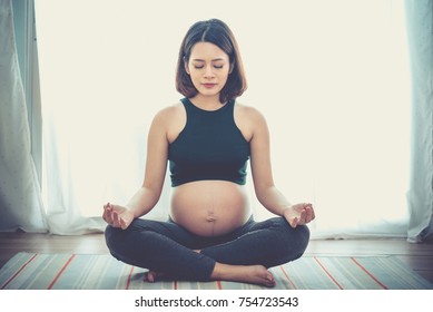 pregnancy, yoga, people and healthy lifestyle concept - happy pregnant woman meditating at home,Vintage style