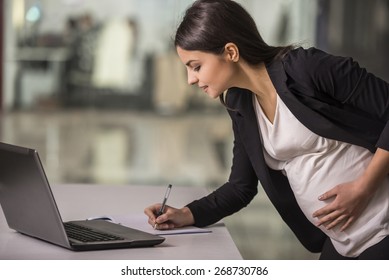 Pregnant adult businesswoman working  at her working place in office.