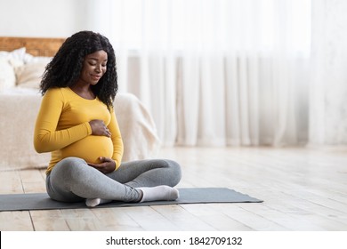 Pregnant african american woman doing morning yoga at home, touching her big tummy, copy space. Young expecting black lady having healthy lifestyle during pregnancy, exercising at bedroom - Powered by Shutterstock