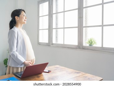 Pregnant Asian woman in the casual office. Working pregnant woman. - Powered by Shutterstock