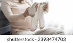 Pregnant asian woman getting ready for the maternity hospital preparing and planning baby clothes for new baby of pregnancy packing for maternity hospital at home 