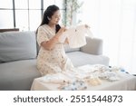 Pregnant asian woman getting ready for the maternity hospital preparing and planning baby clothes for new baby of pregnancy packing baby stuff on bed