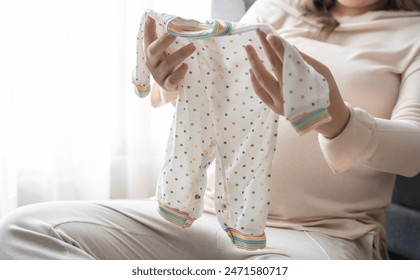 Pregnant asian woman getting ready for the maternity hospital preparing and planning baby clothes for new baby of pregnancy packing for maternity hospital at home  - Powered by Shutterstock