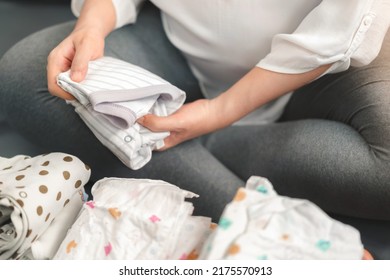 Pregnant asian woman prepare fold baby clothes for planning new born baby, Prepare before Give birth baby concept. - Powered by Shutterstock