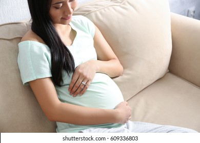 Pregnant Asian woman sitting on sofa at home - Shutterstock ID 609336803
