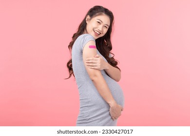 Pregnant Asian Woman smile and happiness after received anti virus vaccine cheerful with bandage isolated on pink background,Pregnancy of young woman enjoying with safety life after got vaccination - Powered by Shutterstock