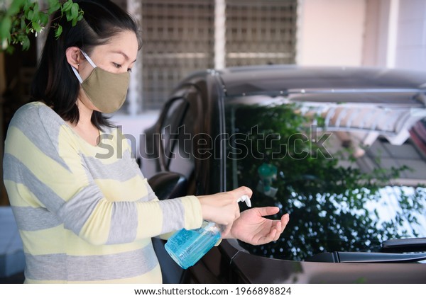 Pregnant asian\
women use ethyl alcohol hand gel before driving by a car, idea and\
concept for coronavirus,\
COVID-19