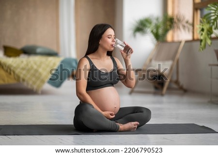 Pregnant Beautiful Woman Drinking Water From Glass While Practicing Yoga At Home, Young Expectant Female In Activewear Embracing Pregnant Belly And Enjoying Healthy Refreshing Drink, Copy Space