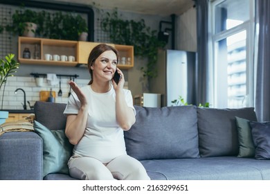 Pregnant beautiful woman sitting on the couch at home, talking on a cell phone with family, friends, colleagues. Has a good mood - Powered by Shutterstock