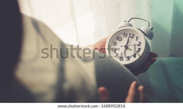 Pregnant\
belly and ticking clock in mom\'s hand. \
Pregnant people are\
watching the clock. To wait for his\
children