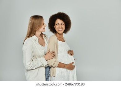 A pregnant Black woman is embraced by her partner, both women are smiling with love and joy. - Powered by Shutterstock