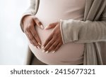 Pregnant black woman holding palms in heart shape on her big tummy, cropped. Unrecognizable african american expecting lady standing by window at home. Pregnancy and maternity concept