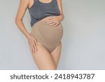 Pregnant bliss: Mom-to-be embraces her baby bump with a soft fabric bandage, providing gentle support. Maternity made comfortable