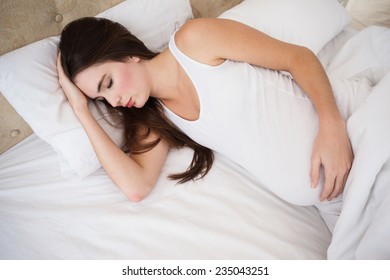 Schwangere Brünette, die zu Hause im Schlafzimmer schlafen
