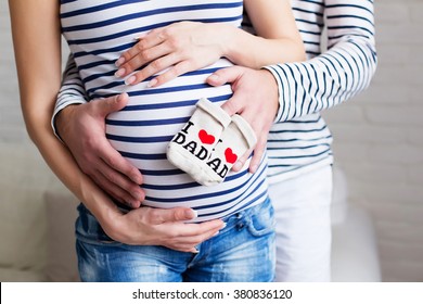 pregnant couple holding baby socks on belly - Powered by Shutterstock