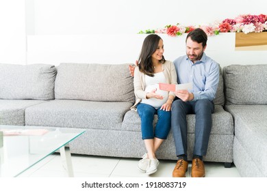 Pregnant Couple Talking About The Medical Services On A Brochure While Sitting At The Waiting Room Of The Gynecologist