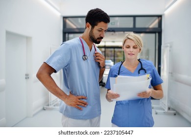 Pregnant doctor talking with her colleague at hospital corridor. - Powered by Shutterstock