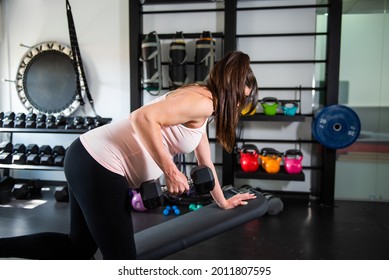 Pregnant Doing Exercises With A Dumbbell In Her Hands To Tone Her Back In A Gym, Side View. Pregnancy