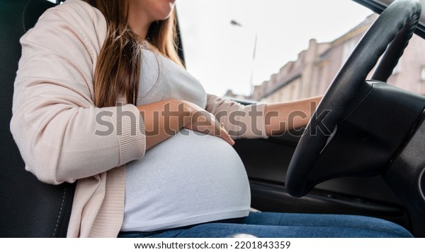 Pregnant driving car.\
Young smiling pregnancy woman driving car. Safety pregnant young\
mom driving concept