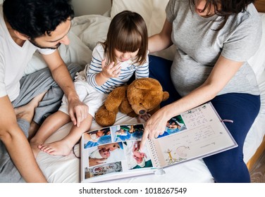 Pregnant Family Looking Through A Family Photo Album