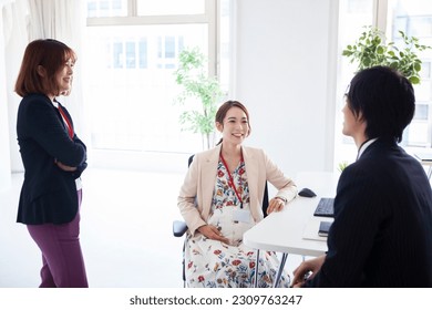 Pregnant female employee chatting with team members - Powered by Shutterstock