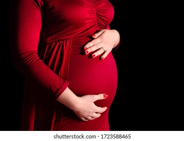 pregnant girl close-up. belly of a pregnant girl close up in a red dress on a black background