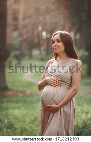 Pregnant girl in nature. Photo taken with selective focus, noise effect and toning.
