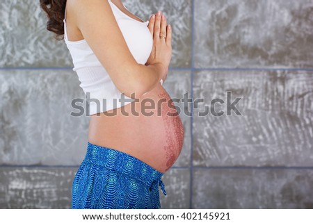 Pregnant girl is standing in yoga pose namaste