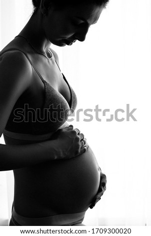 pregnant girl stands by the window