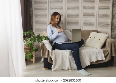 A pregnant girl works remotely at home. Pregnant woman is working on a laptop and smiling. The concept of freelancing and working remotely from the office. Place for text - Shutterstock ID 2092831600